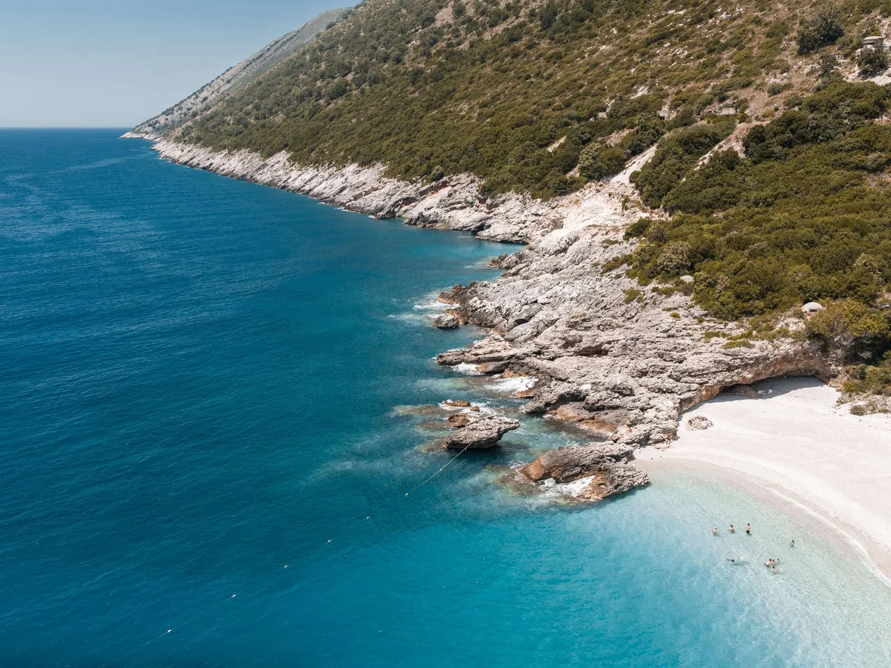Turquoise Ionian water meeting the white coves and green hills of the Albanian Riviera